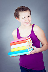 Image showing Silly smiling schoolgirl with glasses and lots of books