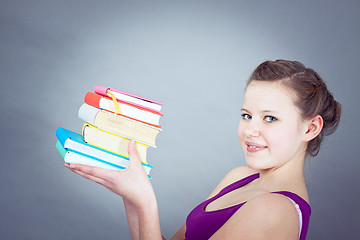 Image showing Silly smiling schoolgirl with glasses and lots of books