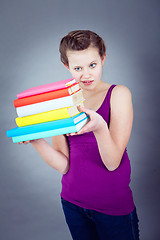 Image showing Silly smiling schoolgirl with glasses and lots of books