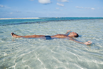 Image showing Man floating in water on the beach