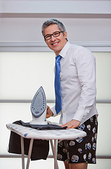 Image showing Businessman smiling while ironing pants