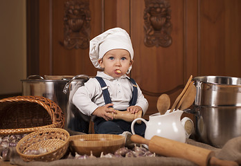 Image showing boy in a cook cap among pans and vegetables