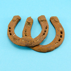 Image showing retro rusty pair upturn horseshoes blue background 