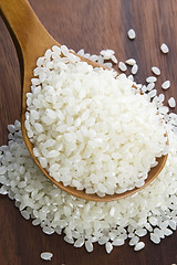 Image showing Rice in wooden spoon on kitchen table