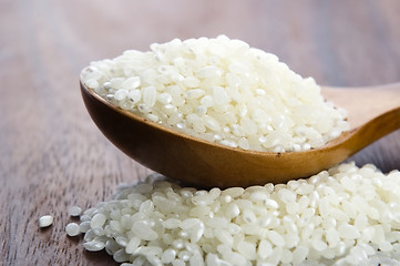 Image showing Rice in wooden spoon on kitchen table