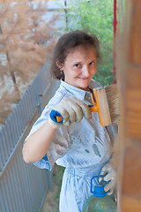 Image showing Pretty woman painting her house