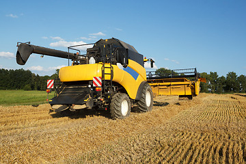 Image showing Yellow harvester combine on field harvesting gold wheat