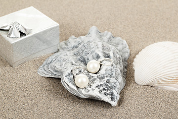Image showing two pearl earrings and shells on sand