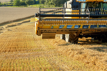 Image showing Yellow harvester combine on field harvesting gold wheat