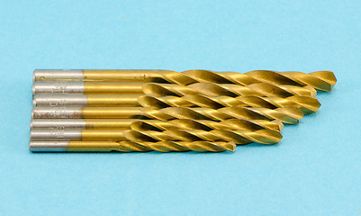 Image showing different size golden color drill bits on blue 