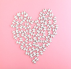 Image showing Puzzle made heart shape on pink background 