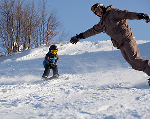 Image showing Man snowboarder and little skier