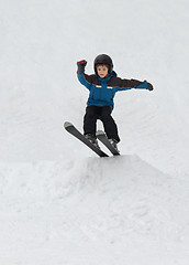 Image showing Little boy jumping on snow skis