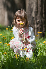 Image showing Little girl sniffing flower