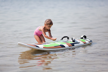 Image showing Little girl and windsurfing board