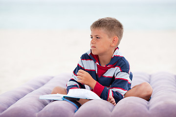 Image showing Beautiful child reading on the beach