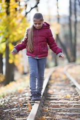 Image showing Girl walking down train tracks
