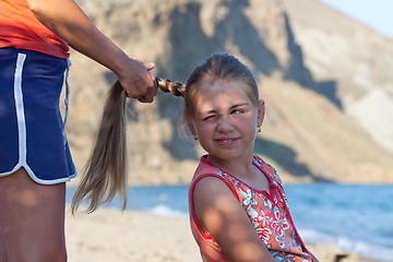 Image showing Mother braiding daughter's hair outdoors