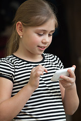 Image showing Little girl typing sms on a smartphone