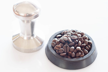 Image showing Roasted coffee in rubber saucer and tamper 