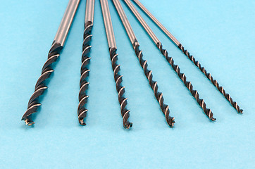 Image showing different size special wood drill bits on blue 