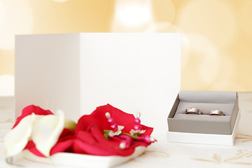 Image showing wedding announcement with rings and space for text, focus wedding anouncement, blurred rings, focus to white paper with space fo