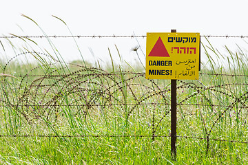 Image showing Razor wire guard fence and warning sign on mines field