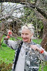 Image showing Woman cuts a branch at an Apple-tree, a spring in the garden 