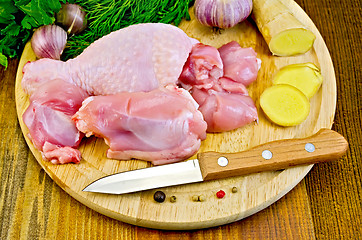 Image showing Chicken leg cut on a wooden board with a knife