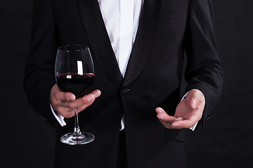 Image showing Fragment of stylish man in elegant black tuxedo with glass red w