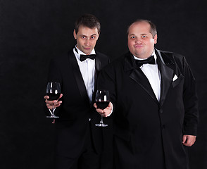 Image showing Two stylish businessman in tuxedos with glasses of red wine