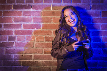 Image showing Mixed Race Woman Using Her Cell Phone Against Brick Wall