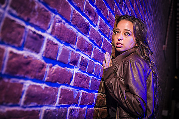 Image showing Frightened Pretty Young Woman Against Brick Wall at Night