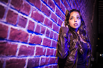 Image showing Frightened Pretty Young Woman Against Brick Wall at Night