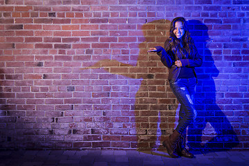 Image showing Mixed Race Woman Holding Her Hand Out Against Brick Wall