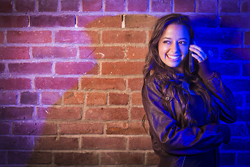 Image showing Mixed Race Woman Using Her Cell Phone Against Brick Wall