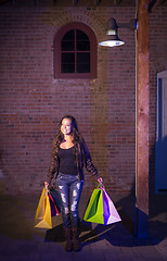 Image showing Mixed Race Young Woman Walking Carrying Shopping Bags at Night