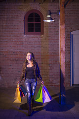 Image showing Mixed Race Young Woman Walking Carrying Shopping Bags at Night