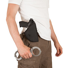 Image showing Close-up of a man with a gun and handcuffs