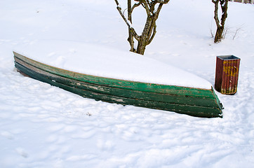 Image showing old wooden boat lying upside down snow bank 