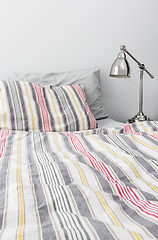 Image showing Metal lamp near bed with colorful bedclothes