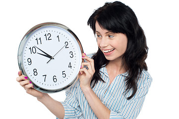 Image showing Pretty girl holding and looking at wall clock