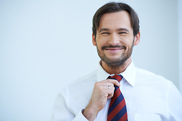 Image showing Happy bearded man straightening his tie