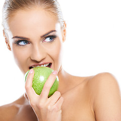 Image showing Woman tries to bite a fresh green apple