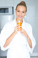 Image showing Woman in bath robe drinking orange juice