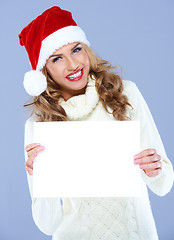 Image showing Smiling woman in Santa hat holding blank board