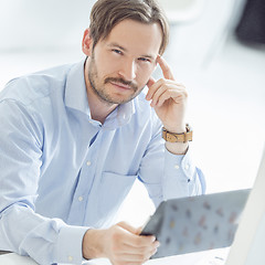 Image showing Young hansome businessman sitting at the desk