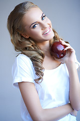 Image showing Head shot of woman holding red apple against grey
