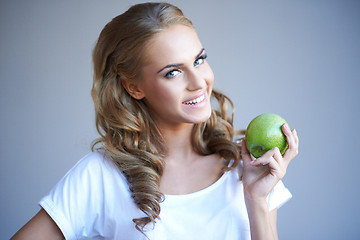 Image showing Head shot of woman holding green apple against grey