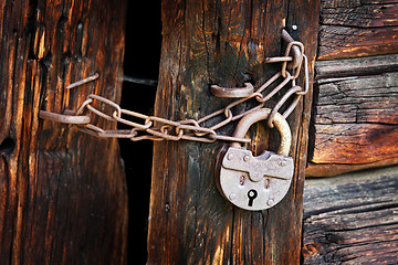 Image showing Old rusty padlock on rural wooden gate